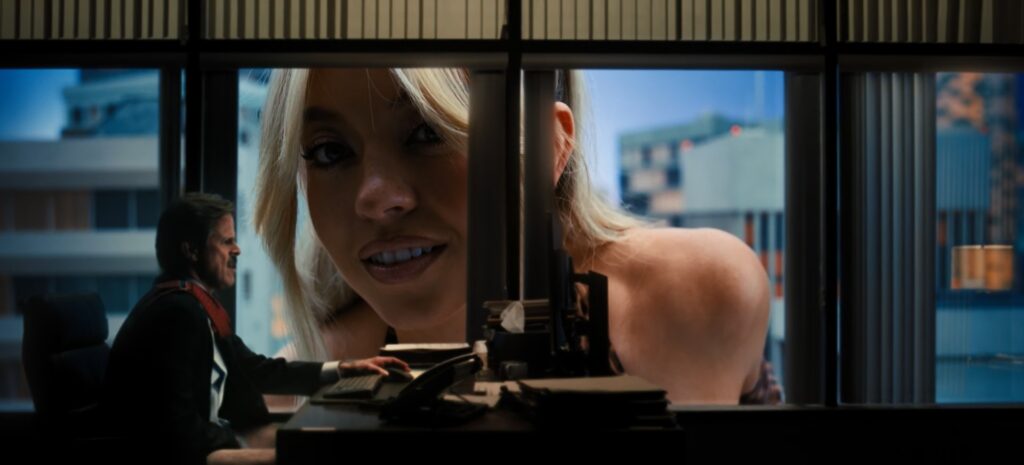 Giant Cassie Howard, played by Sydney Sweeney, leans toward office windows in downtown Los Angeles while a man inside watches her in shock during a surreal fantasy sequence in Euphoria.