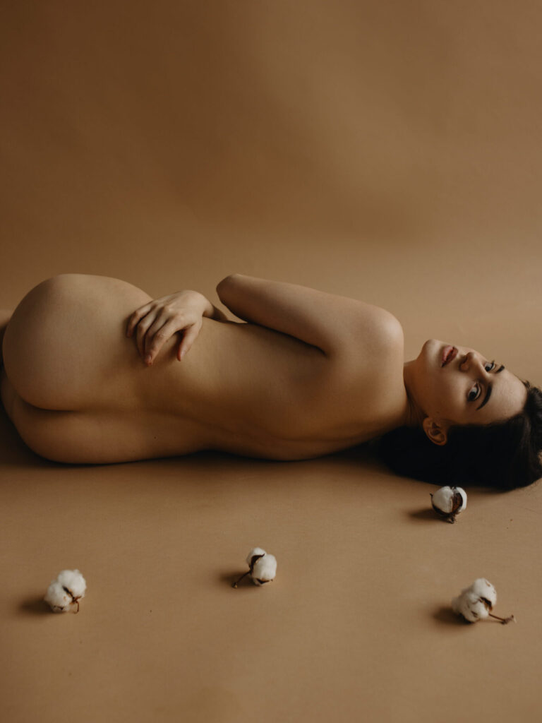 Fine-art portrait of Anastasia Mihaylova (fine-art photographer) lying down completely nude and unclothed on a neutral studio backdrop from the Delicate Cotton series.